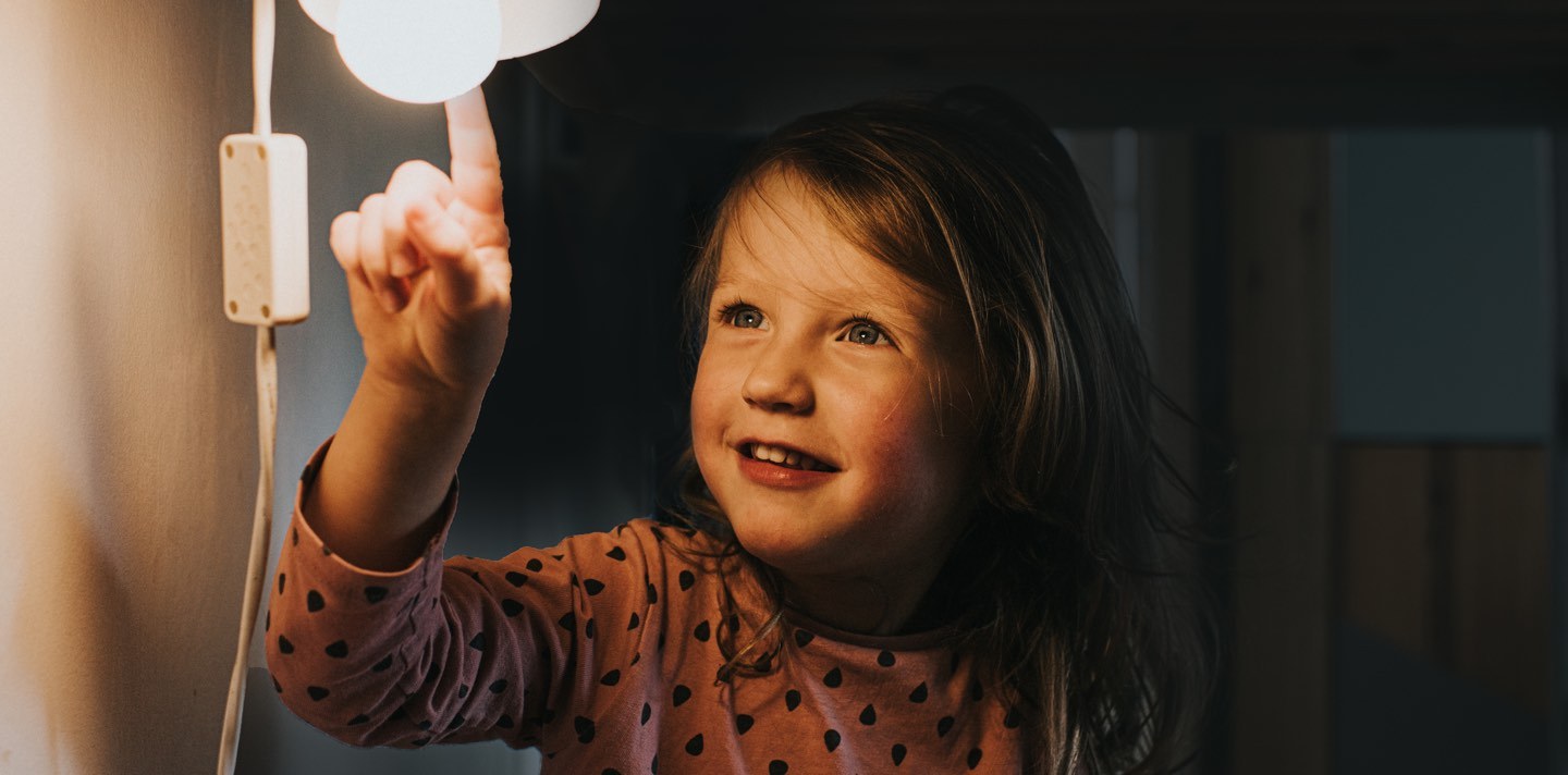 Flicka i mörkt rum tänder en lampa