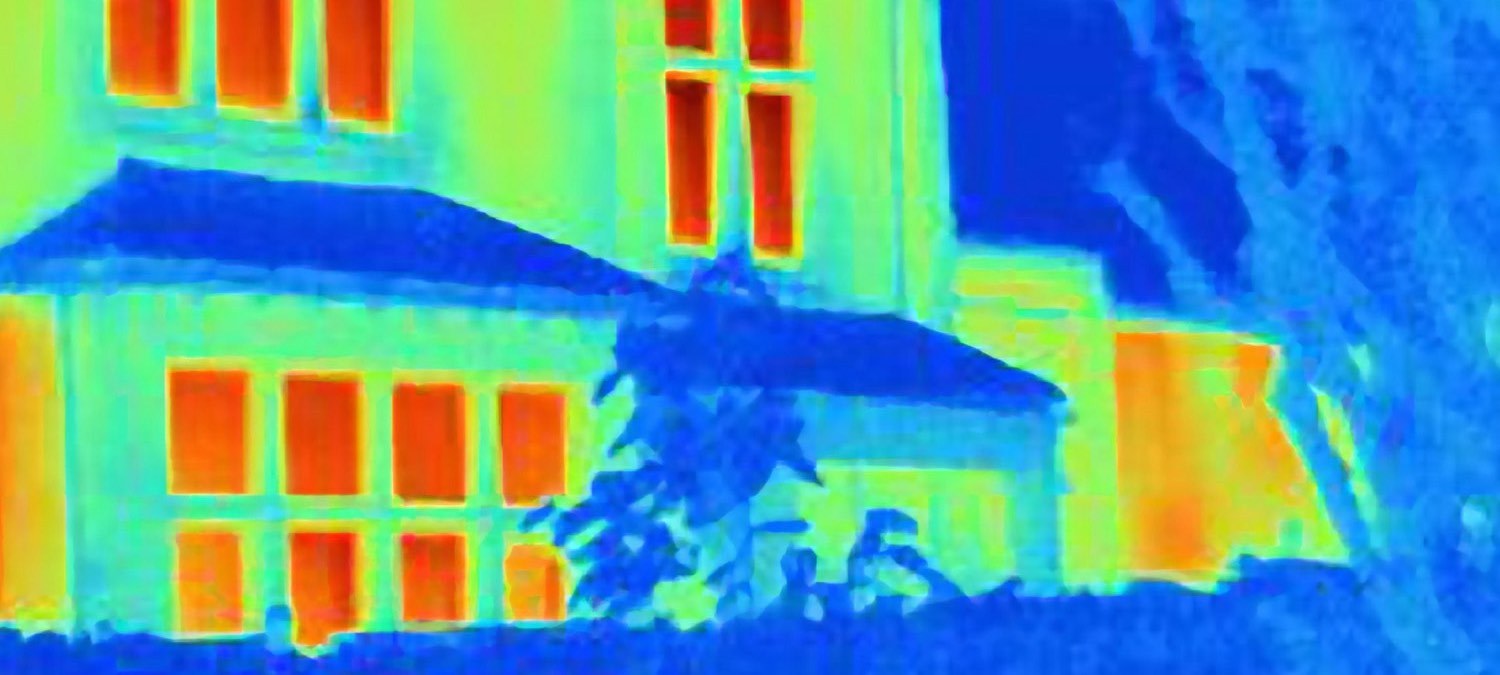 Infraröd bild på husfasad där fönster och dörrar läcker värme